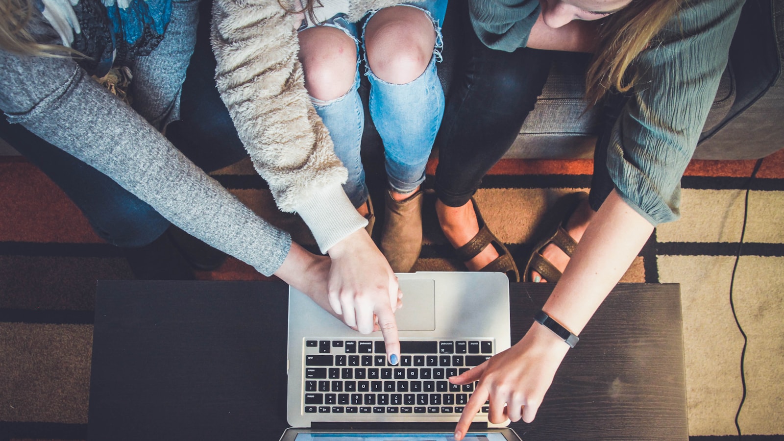 Three people gathered around a laptop reviewing the same screen together