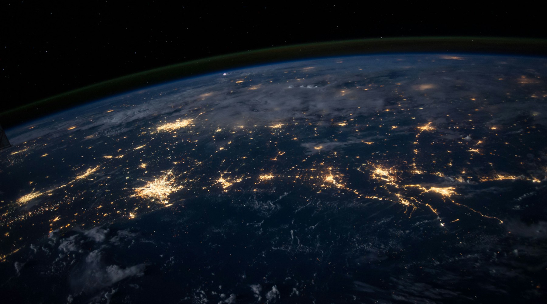 Earth at night from orbit, city lights outlining inhabited regions